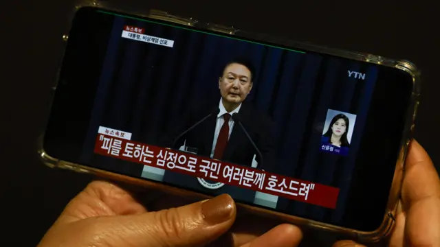 A person watching Yoon's speech on a smartphone