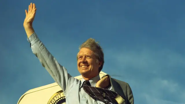 A handout photo provided by the Jimmy Carter Library shows former US President Jimmy Carter waving atop the steps of Air Force On