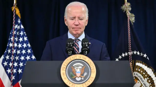 Joe Biden stands at a podium with an American flag behind him