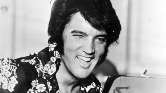 A black-and-white image of Elvis Presley laughing