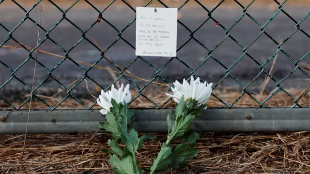 Flowers and a message of condolence laid by people working at the site where an aircraft went off the runway and crashed, are pictured at Muan International Airport in Muan, South Korea