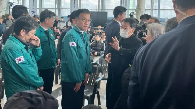 Acting president Choi stands in a green jacket at Muan airport, where he is meeting victims' families