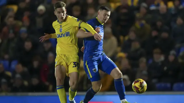 Josh Kelly of AFC Wimbledon ahead of Sam Gale of Gillingham