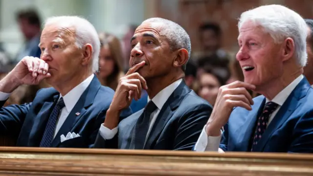 Biden, Obama and Clinton sit side-by-side, each with their hand up to their chin