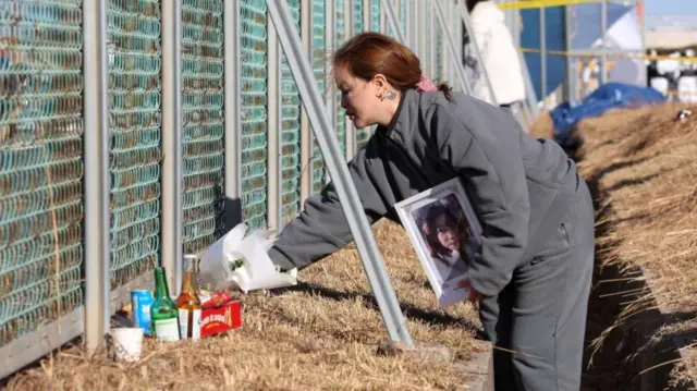 A family member of a Thai victim in the Jeju Air plane crash visits the crash site of Muan International Airport