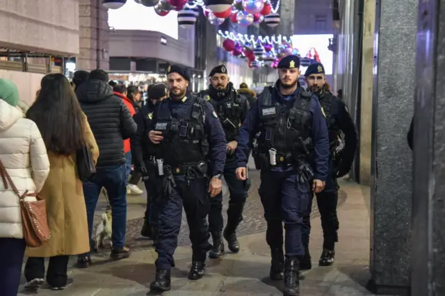 Four policemen walking along a busy street towards the camera