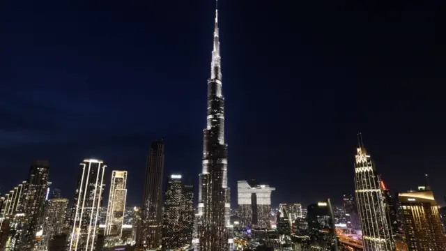 The world's tallest building, the Burj Khalifa at night with city lights around it.