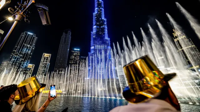 Party-goers wear gold hats watching the water show in front of the Burj Khalifa.