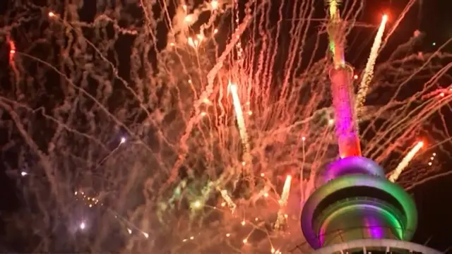 Streams of fireworks in New Zealand sky next to the city's Sky Tower