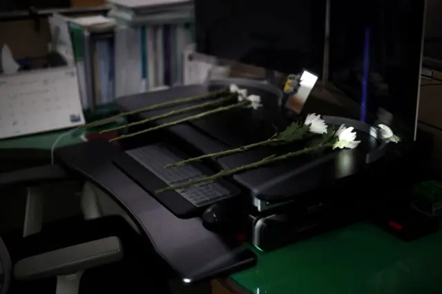 Four white condolence flowers on a desk