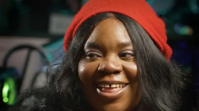 Cassie smiles, wearing a red beret