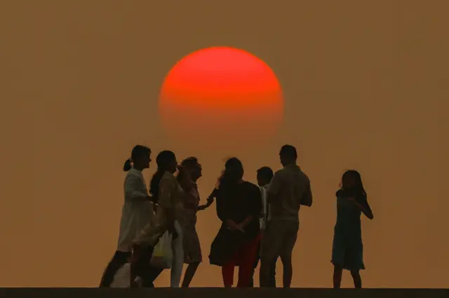 People enjoy the last sunset of the year on New Year's Eve at Gorai beach along the Arabian Sea coast, on the outskirts of Mumbai, India