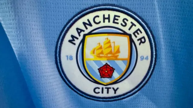 A close up of Manchester City's badge on their shirt.