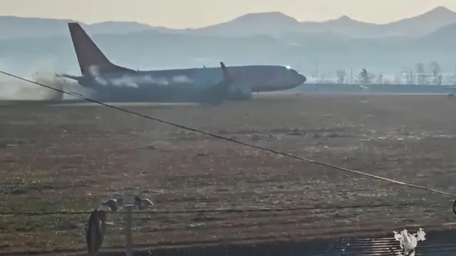 Black smoke emits from Jeju Air aircraft flight 7C2216 as it veers off the runway. It appears that the landing gear has not been lowered