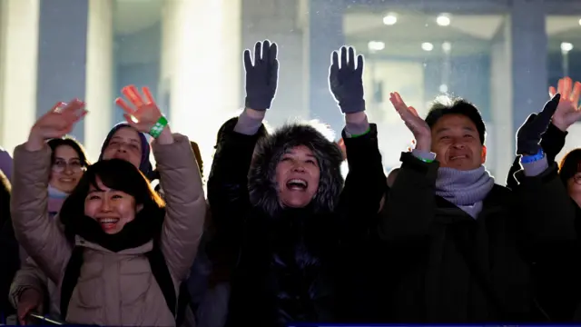 Crowds in Tokyo clap and raise their hands in the air to celebrate the new year