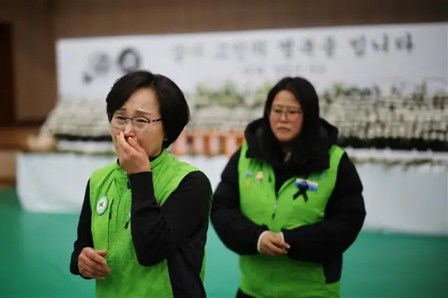 Lee Kwi-sun reacts after mourning in Muan, with her hand over her mouth against the backdrop of a memorial alter