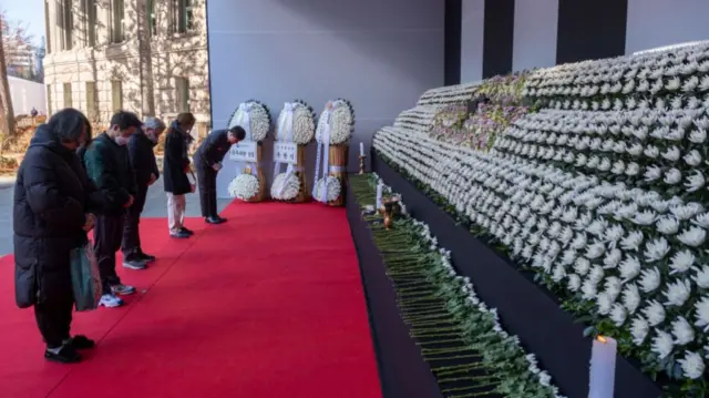 People pay their respects at an altar in front of Seoul City Hall