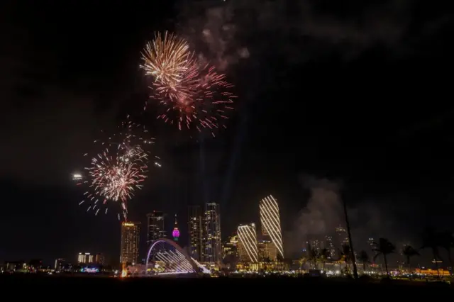 Fireworks in front of a lit up skyline and a bridge