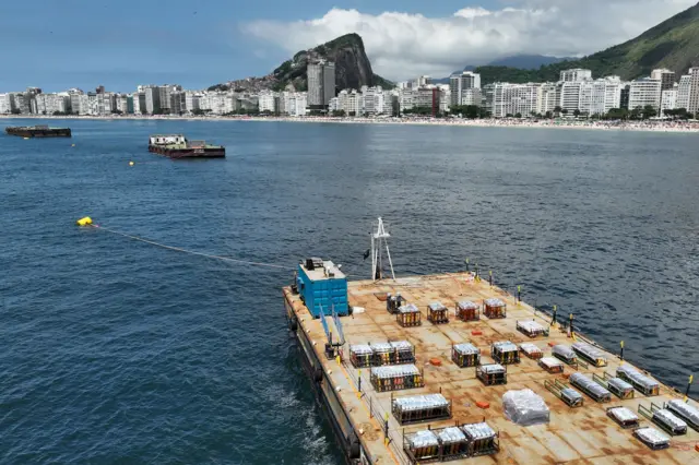 Barge loaded with boxes of fireworks in front of Rio's skyline