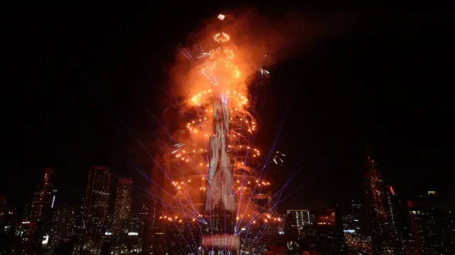 Orange fireworks create circles around the Burj Khalifa in Dubai at night.