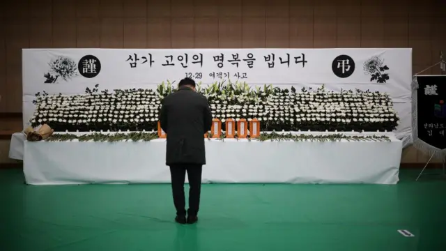 A man mourns at a memorial altar for government officials of Jeollanam-do Office of Education and students who died in the Jeju Air crash at Muan International Airport