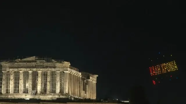 Drones forming Greek words behind the Parthenon which is lit up