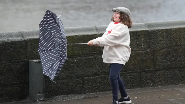 A girl struggles to keep hold of an inverted umbrella as  the wind picks up in Dublin's city centre