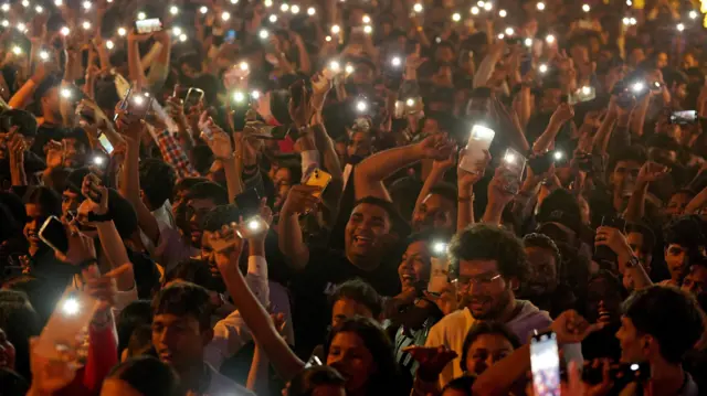 People flash lights from their mobile phones as they attend New Year’s Eve celebrations in Mumbai