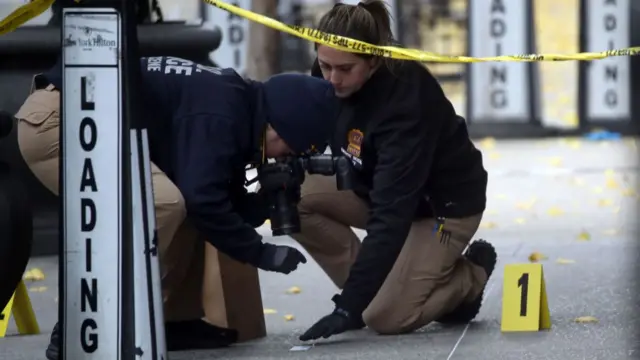 Police place bullet casing markers outside of a Hilton Hotel in Midtown Manhattan where United Healthcare CEO Brian Thompson was fatally shot