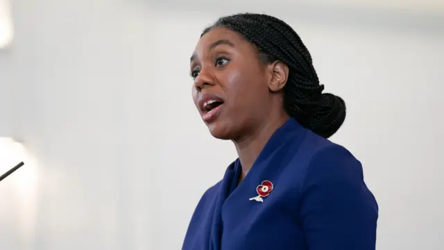 Kemi Badenoch making a speech wearing a blue dress