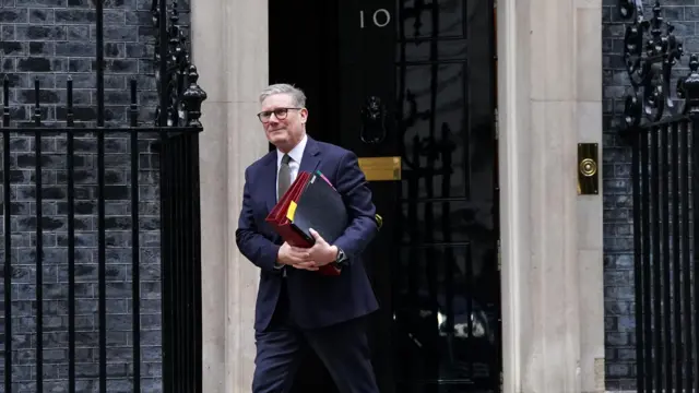Prime Minister Sir Keir Starmer departs 10 Downing Street, wearing a suit and carrying a bundle of files