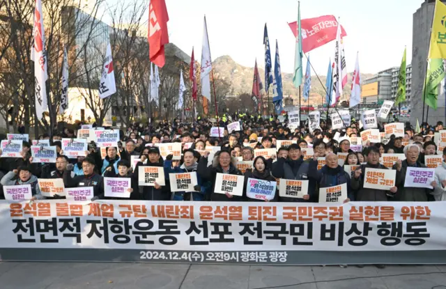 South Korean protesters hold a banner that read "we condemn Yoon Suk Yeol's illegal martial law" during a rally