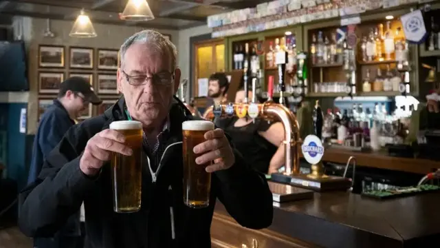 Man holding two pints in a pub