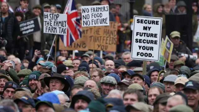 Farmers taking part in a demonstration holding signs reading 'Stop the family farm tax,' 'No farmers, no food, no future' and 'Secure my future, secure your food.'