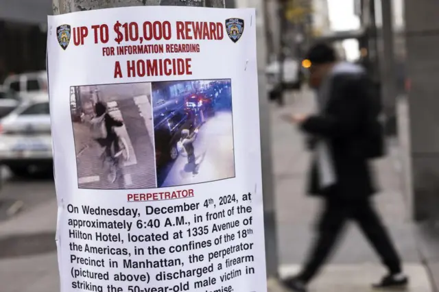 Close up on a Wanted notice on a pole outside the Hilton Hotel in New York. Reads "Up to $10,000 Reward for information regarding a homicide" with images of the suspect.