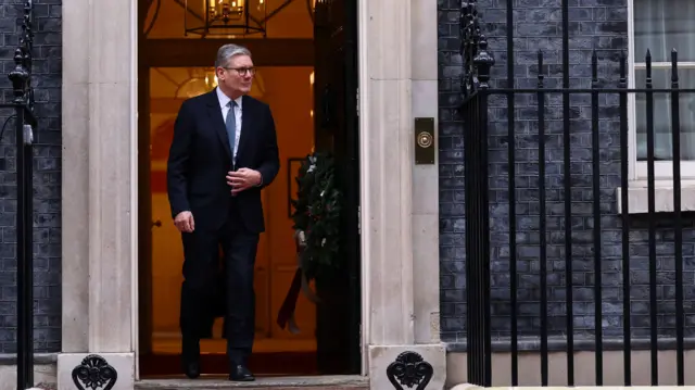 British Prime Minister Keir Starmer steps out of No 10 and looks down the street