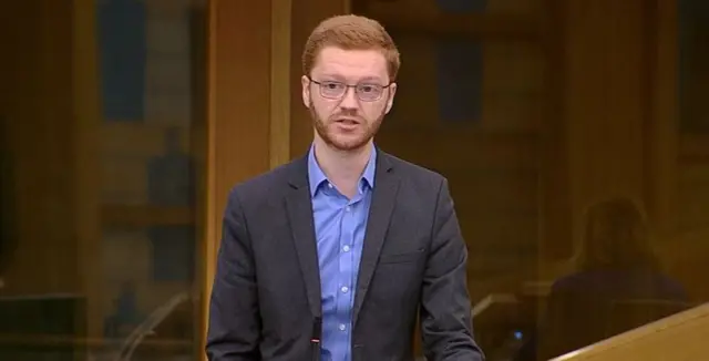 Ross Greer in the chamber, wearing a blue shirt and dark grey jacket