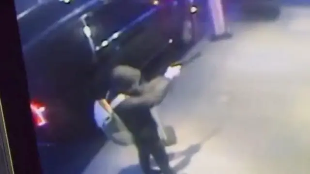 A suspect holds a weapon before shooting an insurance CEO