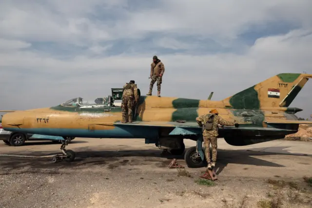 Syrian rebel forces on top of a Syrian army jet after they captured the city Hama