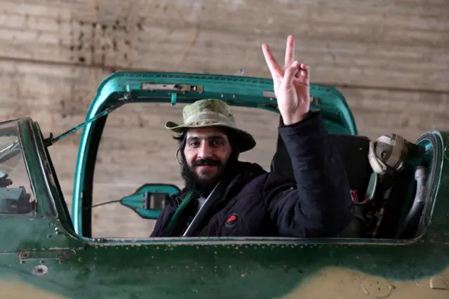 An anti government fighter gestures a peace sign in the cockpit of a Syrian army jet