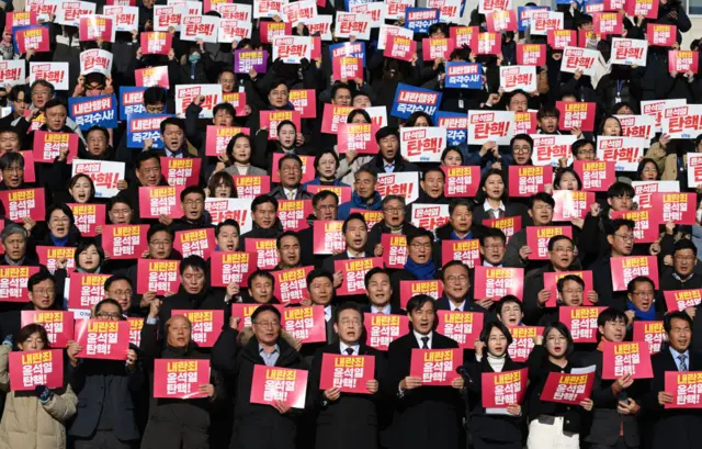 Opposition lawmakers and activists hold placards reading "Impeach Yoon Suk Yeol for rebellion!"