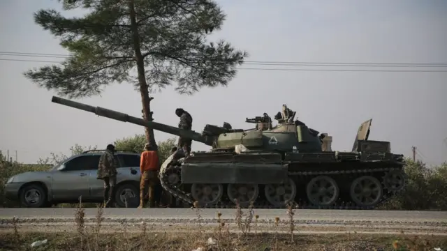 Opposition fighters stand on a tank of the Syrian government after they entered the city of Hama, Syria, 06 December 2024