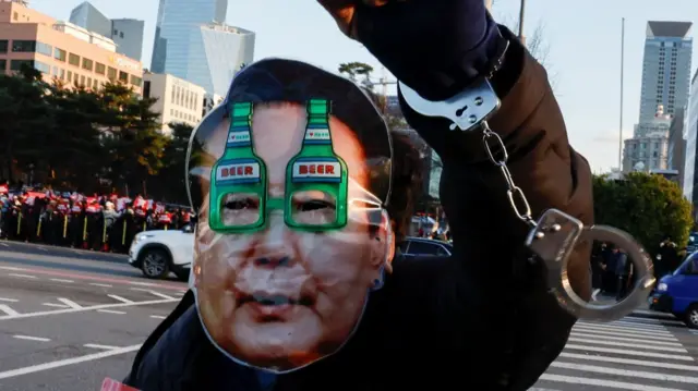 Protester wearing a Yoon face mask and dangling handcuffs