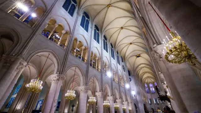 Wide shot of restored roof of Notre-Dame cathedral illuminated by candelabra and heavy-duty lights