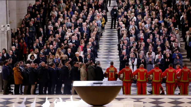 Guests applaud firefighters, rescuers and builders involved in the restoration of the Notre Dame de Paris cathedral, during its official reopening ceremony, in Paris