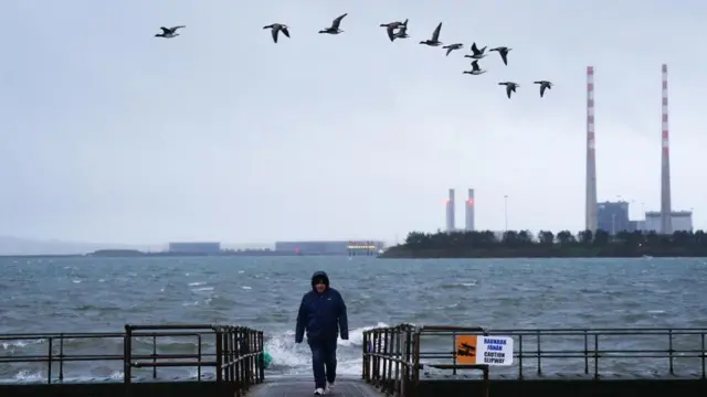 A person on a slipway in Clontarf, Dublin, with stormy seas and skies