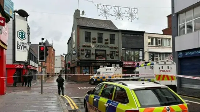 Police cars in Belfast city centre, with a green pub in the centre