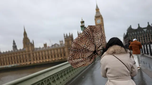 A woman holds her umbrella during a gust of wind on Westminster Bridge after Storm Darragh hit the country, in London