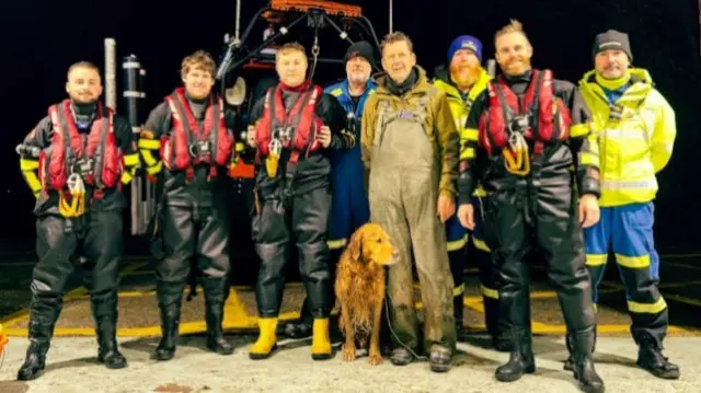 Buddy the dog stands for a group photo with the team at Humber rescue, after he arrived at the station. The four crew members are still in their life jackets and wellies.