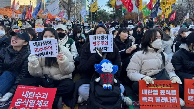 University students hold placards asking for Yoon's arrest